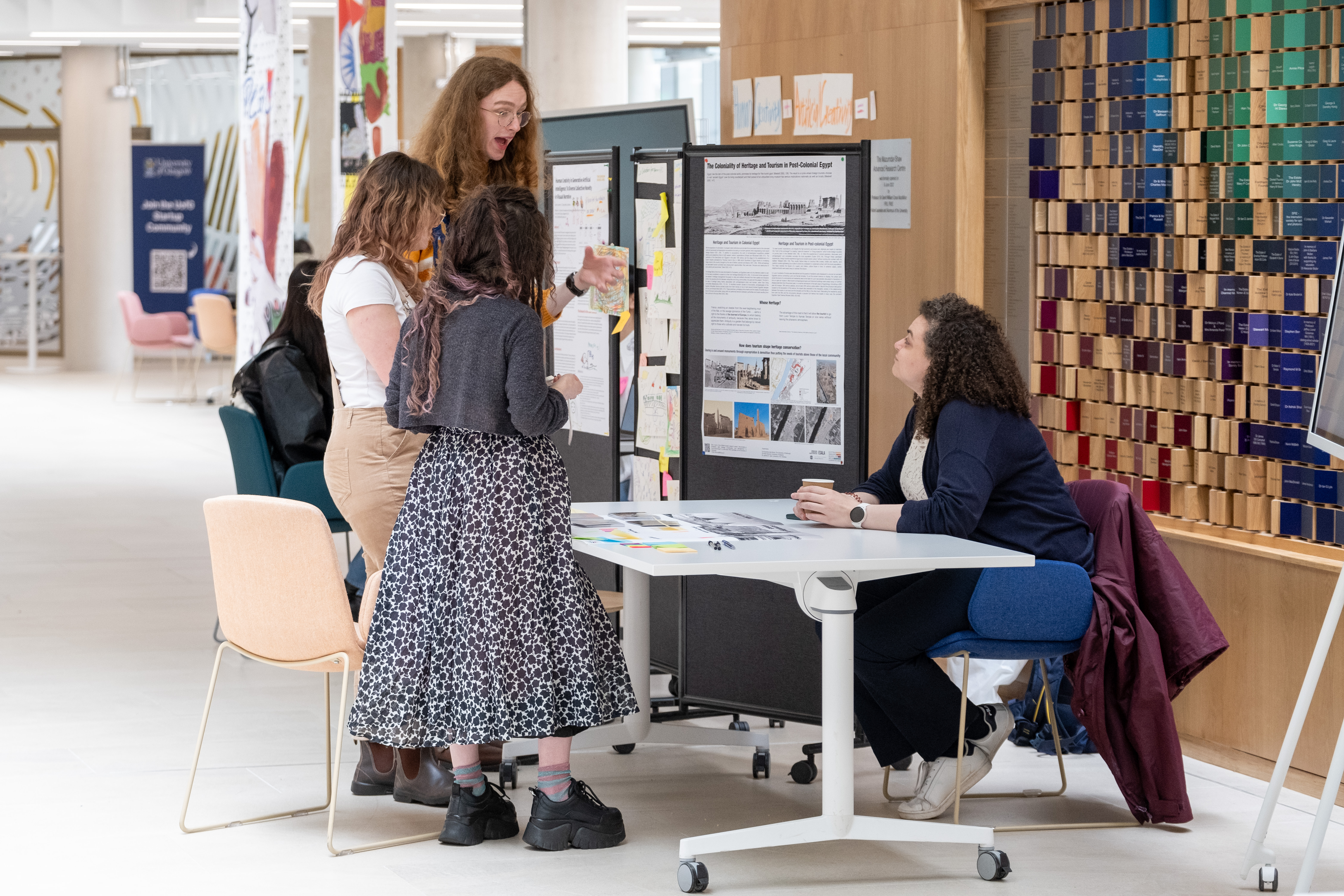 three onlookers discuss a research display with its owner